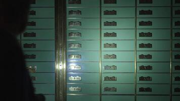 A mysterious figure opens safe deposit boxes in a dark vault, shrouded in secrecy video