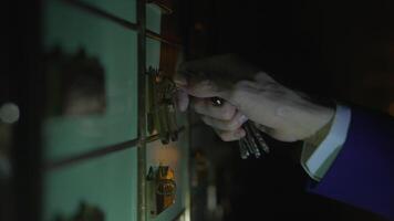 A hand operating a safe deposit box with keys in a secure vault video