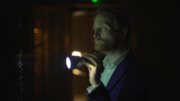 man i mörk rum med ficklampa, utseende allvarlig och fokuserad, utforska med koncentration video