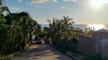 Colorful street with houses palms cars jungle Puerto Escondido Mexico. video