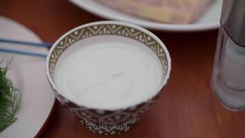 greens on a plate and sour cream in a saucepan stand on the table, ingredients video