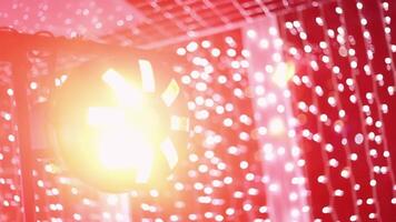 Vintage multi-colored disco lighting of round shape on stand against background of an LED curtain curtain shines with rays, falling into lens. Focus changes, image becomes blurry with beautiful bokeh. video