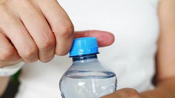 Bottle with stationary plastic cap in woman hand. The new design means the cap remains attached to the bottle after opening, making the entire package easier to collect and recycle. 4k footage video