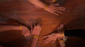 Haut vue de diverse mains ensemble sur une en bois surface, symbolisant unité et travail en équipe, avec chaud bracelets video