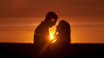 silhouet, strand en paar Bij zonsondergang kus voor binding, samen en verhouding door oceaan. daten, natuur en Mens en vrouw met genegenheid en liefde voor romance Aan vakantie, vakantie en weekend. video