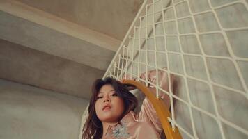 Young woman leaning on a railing, looking pensively downwards, with a geometric background. video