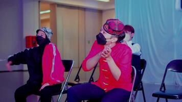 groep van jong dansers repeteren in een studio, vervelend gewoontjes straat slijtage en gezicht maskers, met focus Aan een persoon in een rood jasje video