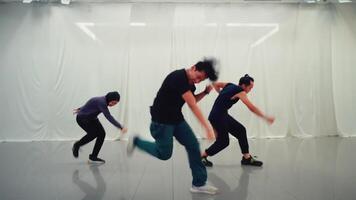 drei Tänzer üben im ein Studio mit ein durchscheinend Vorhang Hintergrund, zeigen Bewegung und Energie. video