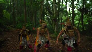 Three performers in traditional Balinese costumes and masks dancing in a lush forest setting, showcasing cultural heritage video