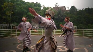 tradizionale asiatico interpreti nel colorato costumi e maschere impegnato nel un' dinamico culturale danza all'aperto video