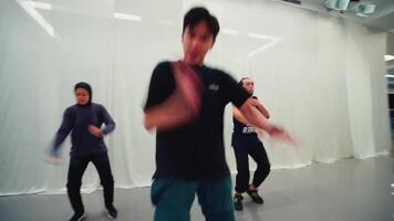 dynamisch groep van jong volwassenen beoefenen stedelijk dans beweegt in een studio met een wit achtergrond, presentatie van energie en modern dans cultuur. video