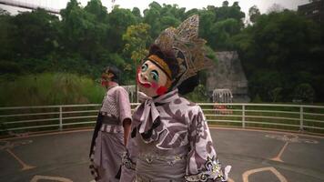 Traditional Chinese opera performer in elaborate costume and painted face mask, showcasing cultural dance in an outdoor setting video