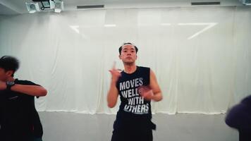 Three young adults practicing a dance routine in a modern dance studio with mirrors and bright lighting video