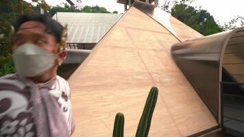 Person in traditional attire taking a photo of a plant with a tablet in a greenhouse setting. video