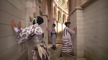 Three individuals in traditional Asian attire and face masks standing in an ornate stairwell, showcasing a blend of cultural heritage video