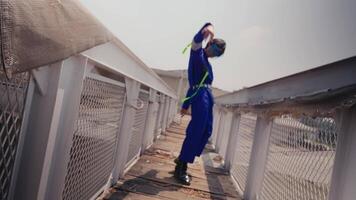 Stylish person in blue and neon outfit standing on a rooftop with urban skyline in the background. video