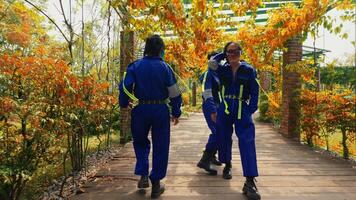 Team of gardeners with tools walking on a path surrounded by autumn foliage. video