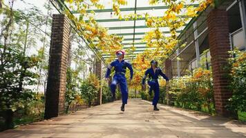 Two workers in blue uniforms walking through a greenhouse with autumn foliage. video