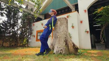 arbeider in beschermend uitrusting gebruik makend van een kettingzaag naar besnoeiing een boom stomp in een woon- Oppervlakte. video