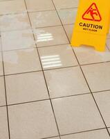 Caution wet floor warning sign on the floor, closeup of photo