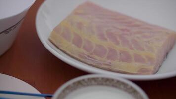 A fresh sturgeon fillet lies on a white platter, the fish in a marinade video