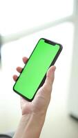 Vertical of hand using phone green screen in home, green screen of smartphone, hand holding mobile phone, hand touchscreen smartphone video