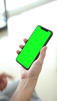 Vertical of hand using phone green screen in home, green screen of smartphone, hand holding mobile phone, hand touchscreen smartphone video