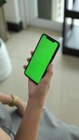 Vertical of hand using phone green screen in home, green screen of smartphone, hand holding mobile phone, hand touchscreen smartphone video