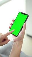 vertical de mano utilizando teléfono verde pantalla en hogar, verde pantalla de teléfono inteligente, mano participación móvil teléfono, mano pantalla táctil teléfono inteligente video