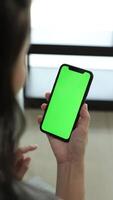 Vertical of hand using phone green screen in home, green screen of smartphone, hand holding mobile phone, hand touchscreen smartphone video