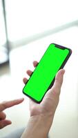 Vertical of hand using phone green screen in home, green screen of smartphone, hand holding mobile phone, hand touchscreen smartphone video