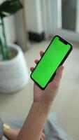 Vertical of hand using phone green screen in home, green screen of smartphone, hand holding mobile phone, hand touchscreen smartphone video