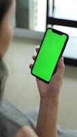 Vertical of hand using phone green screen in home, green screen of smartphone, hand holding mobile phone, hand touchscreen smartphone video