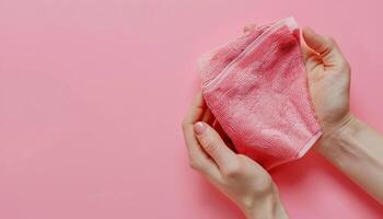 Two Hands Holding Pink Cloth on Pink Background photo