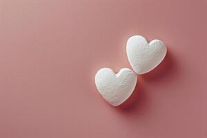 Two Heart Shaped Marshmallows on Pink Background photo