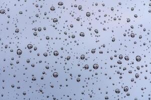 gotas de lluvia en vaso ventana de coche con nublado cielo en el antecedentes 2 foto