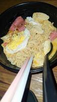 Noodles with egg and sausage with spoon and chopsticks photo