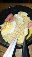 Noodles with egg and sausage with spoon and chopsticks photo