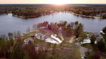 Lakeside neighborhood at sunset, Aerial view of a peaceful lakeside neighborhood with houses surrounded by trees and a serene lake. video