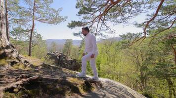 A male hiker climbs up in white clothes without a backpack. Easy ascent in the mountains video