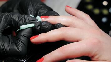 nagel tekniker applicering röd nagel putsa, en nagel tekniker bär svart handskar är försiktigt applicering röd nagel putsa till en klientens naglar video