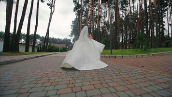 de bruid is rennen in de park in een wit jurk. een ongelukkige bruiloft dag, de bruid loopt weg van de bruiloft ceremonie video