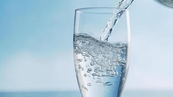 pour water into a transparent glass that stands on the table photo