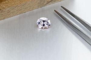 macro mineral faceted stone Morganite with tweezers on a gray background photo
