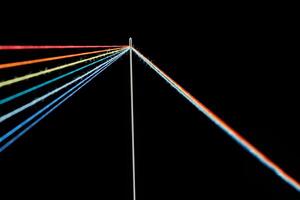multi-colored threads for sewing in the form of a rainbow pass through an antique needle on a black background photo