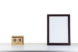 Wooden calendar 09 January with frame for photo on white table and background