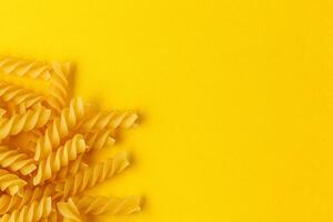 Different types and shapes of dry italian pasta on a yellow background photo