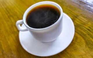 blanco taza de negro americano café en un de madera mesa. foto