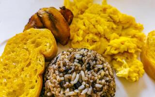 Costa Rican food dish Rice Banana Scrambled eggs Beans bread. photo