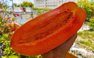 Half papaya in hand with background in Mexico. photo